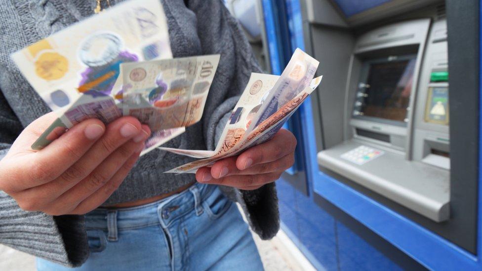 Close up of hands counting money from a cash machine