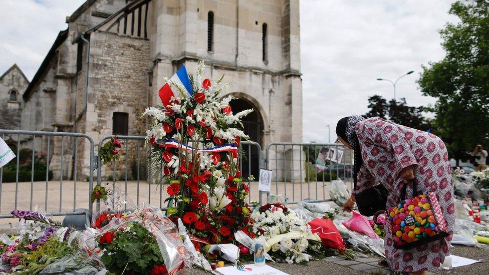 A Muslim woman lays tribute to a murdered Catholic priest