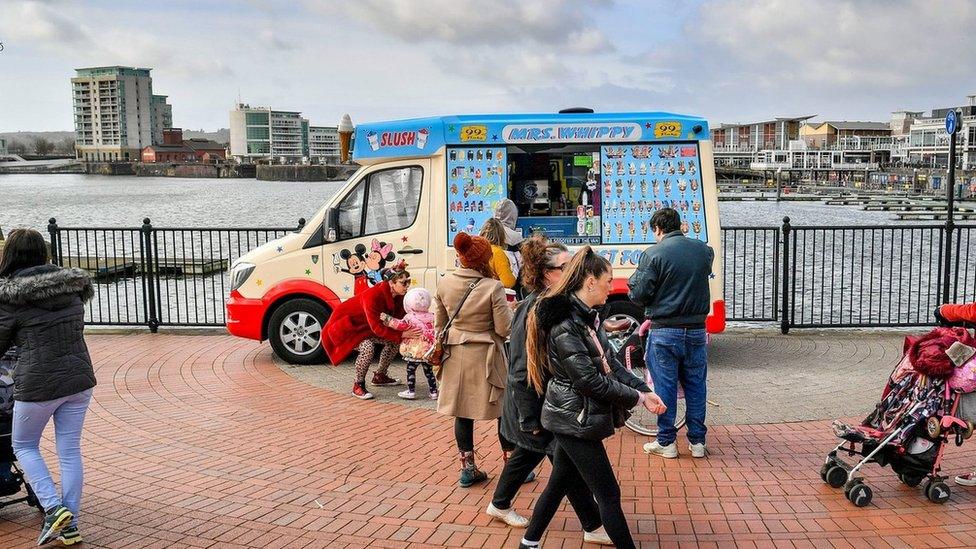 People queue for an ice-cream van in Cardiff Bay, Wales