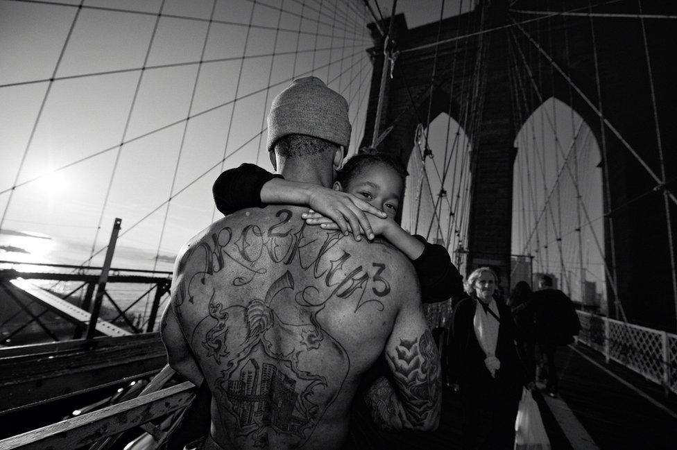 Jerell carrying his son over the Brooklyn Bridge