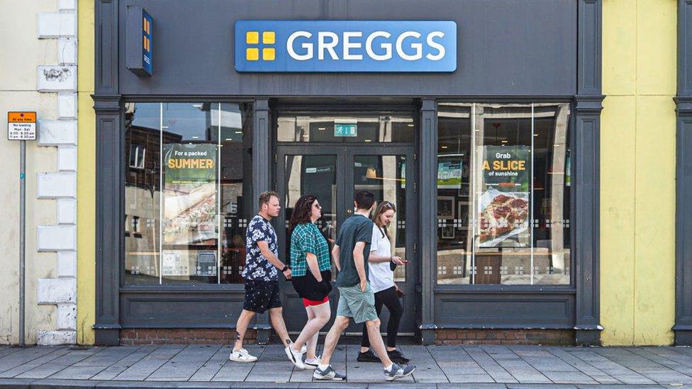 People walk past a Greggs bakery