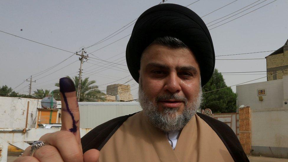 Iraqi Shia cleric Moqtada al-Sadr shows his ink-stained finger after casting his vote at a polling station during the parliamentary election in Najaf on 12 May 2018