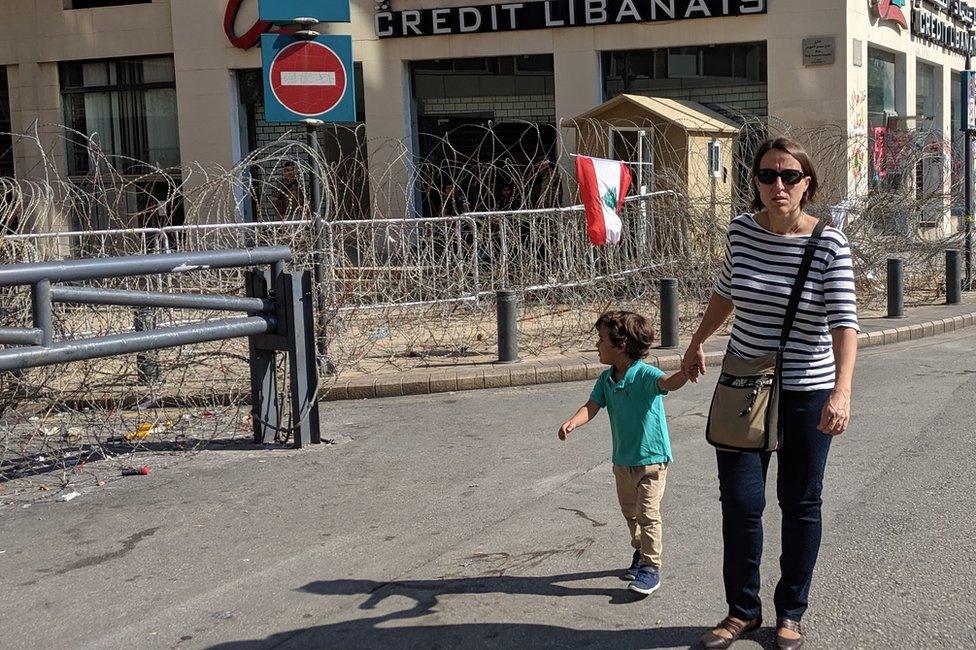 A woman and a child walk past a closed bank in Beirut, Lebanon (4 November 2019)