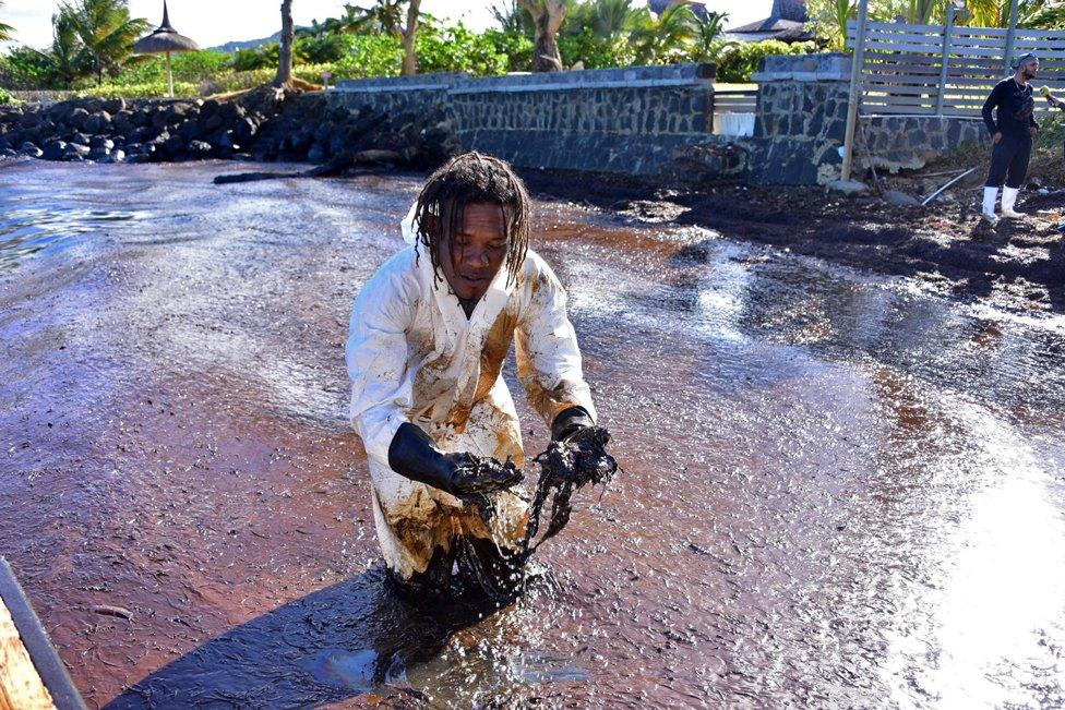 A volunteer stands in leaked oil