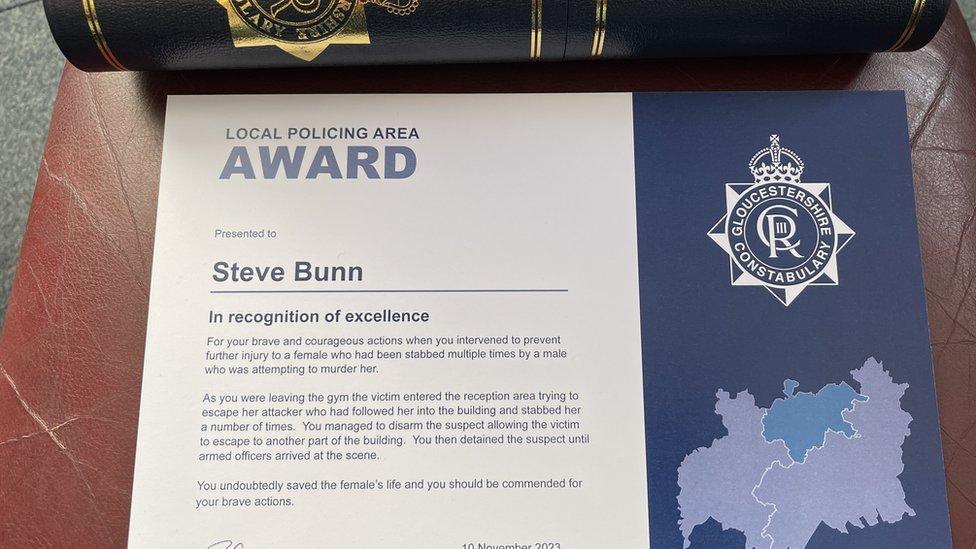 A certificate for Steve Bunn from the Gloucestershire Constabulary "in recognition of excellence", written in blue on a white background, with a smart black and gold tube in the background to contain it.