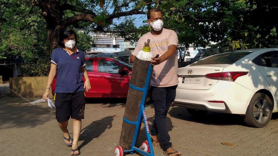 A couple walks with an oxygen cylinder for a Covid-19 coronavirus patient admitted at the Goa Medical College and Hospital.