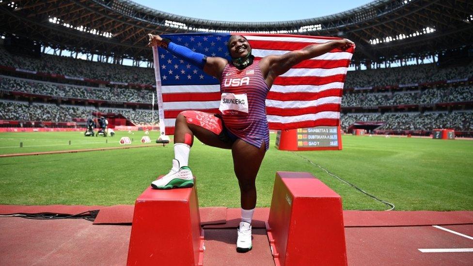 Raven Saunders poses with her national flag as she celebrates winning the silver medal