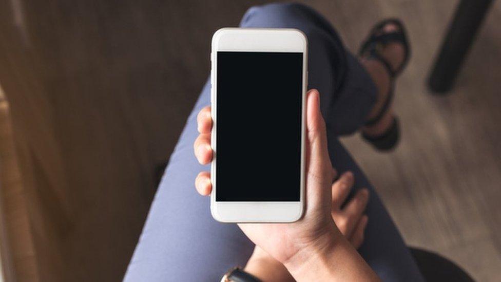 A woman holds a smart phone