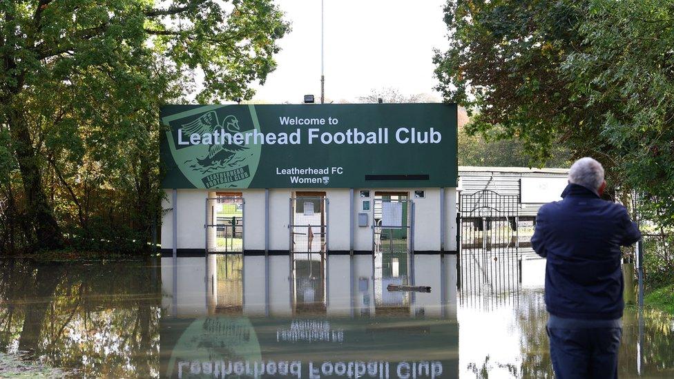 A man views a waterlogged entrance to a football ground as flooding continues in the aftermath of Storm Ciaran, in Leatherhead, southern Britain.