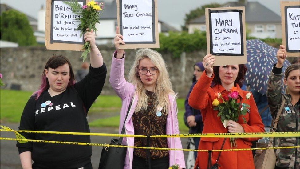 Women hold up placards of the names of babies buried at Tuam