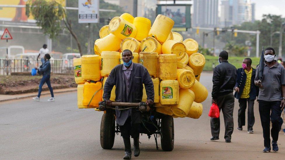 A man pulls a handcart with jerrycans along the street before a curfew, as the spread of the coronavirus disease (COVID-19) continues