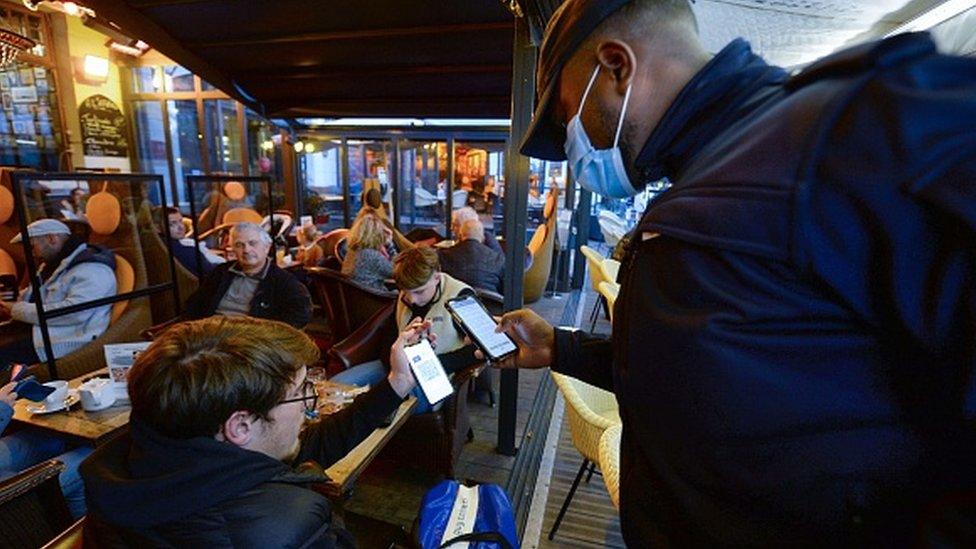 A man at a bar shows a policeman his Covid pass in France