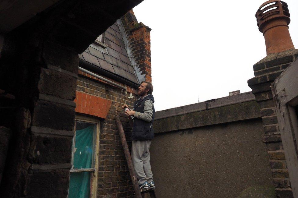 A man on a ladder against the outside of the building