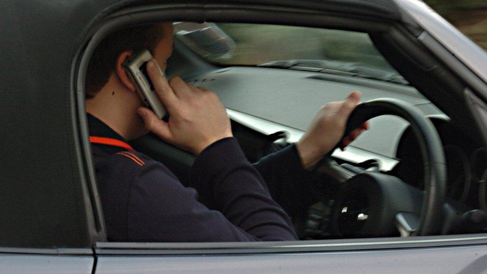 Posed file picture of a man using a mobile phone while driving.