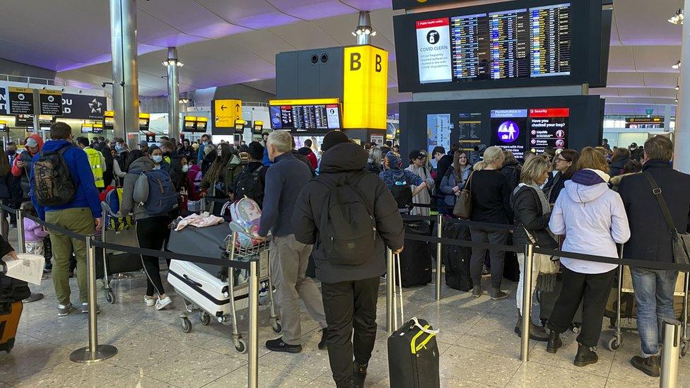 Travellers queue at a check-in desk at Heathrow Airport