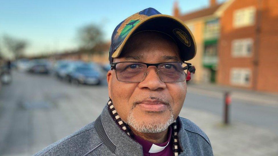 Man with glasses wearing a cap and standing outside