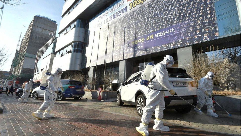 Workers sanitize a street in front of a branch of the Shincheonji Church