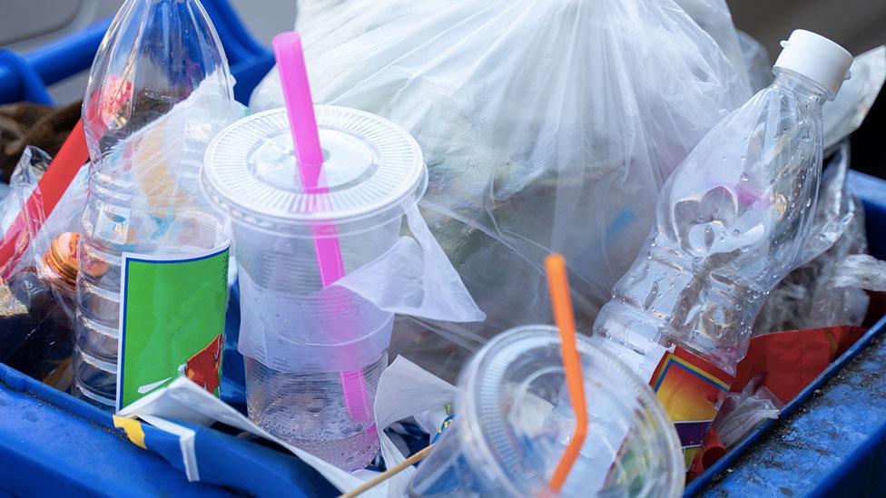 Plastic bottles and cups in an overflowing bin