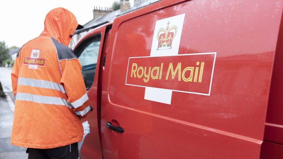 A royal mail postal worker getting into his red van