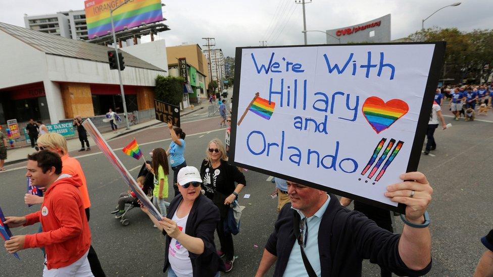 A man holding a 'we're with Hillary and Orlando' sign