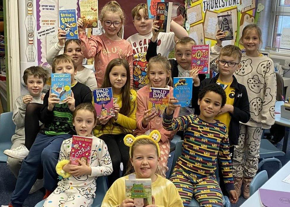 A group of children each holding a book