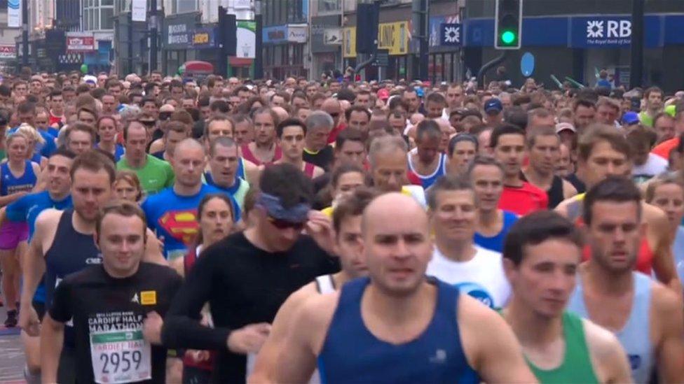 An image of the Cardiff Half marathon - with lots hundreds of runners tightly packed together in Cardiff.