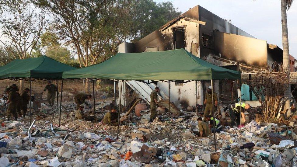 Israeli soldiers and volunteers from the Zaka Israeli ultra-Orthodox Jewish emergency response team searches through the debris in Kibbutz Be'eri near the border with Gaza on 12 November 2023, in the aftermath of an attack by Palestinian militants on October 7.