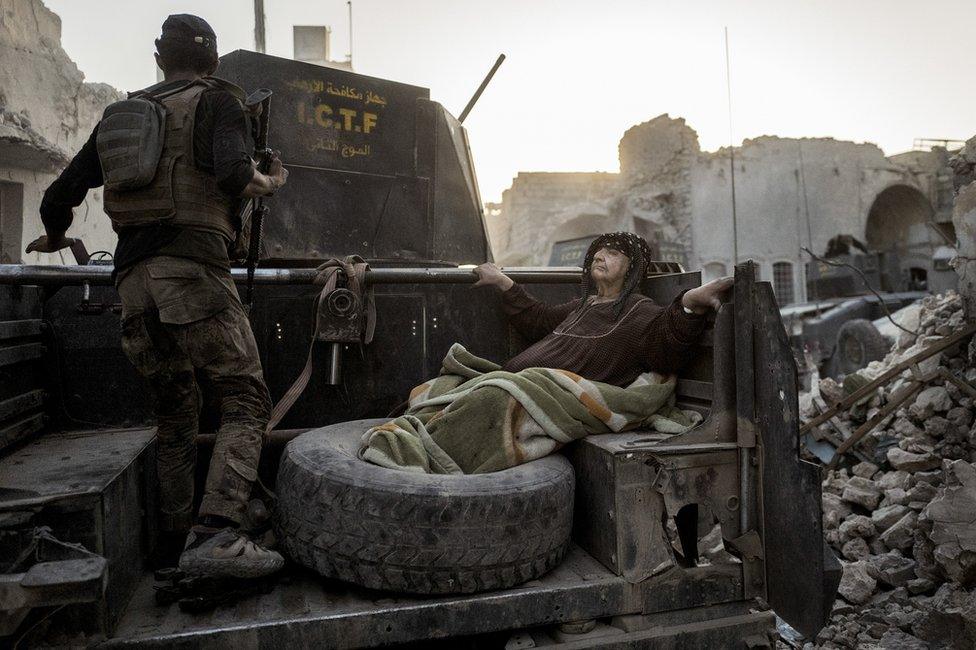An elderly woman is driven through Mosul, Iraq, as the Golden Division help her flee the front line in extreme heat.
