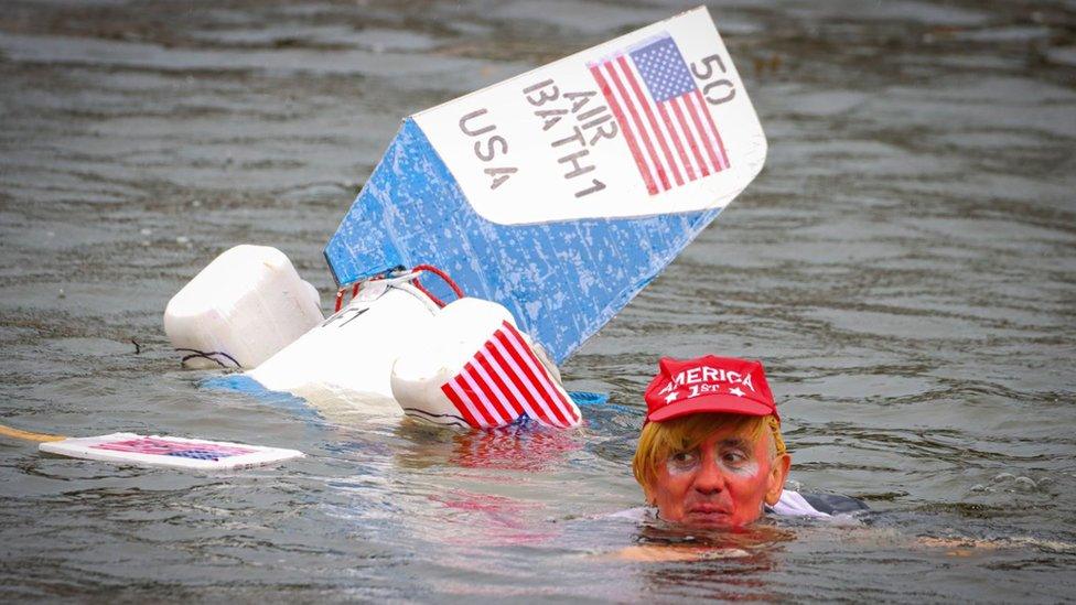 Competitor in fancy dress swimming away from his sinking tin bath