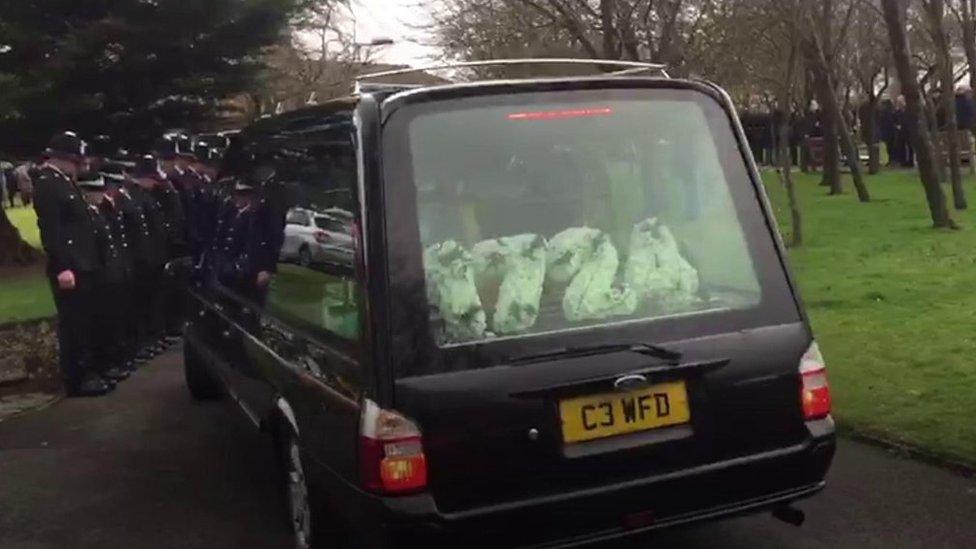 Police officers line the route as the hearse drives past