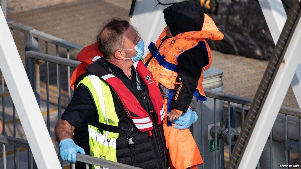 A Border Force official carries a young migrant to safety