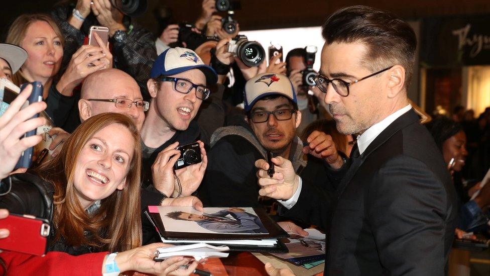 Colin Farrell signs fan memorabilia on the red carpet