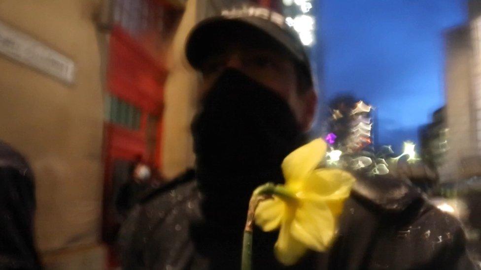 A blurred shot of a police officer with a daffodil in front of them