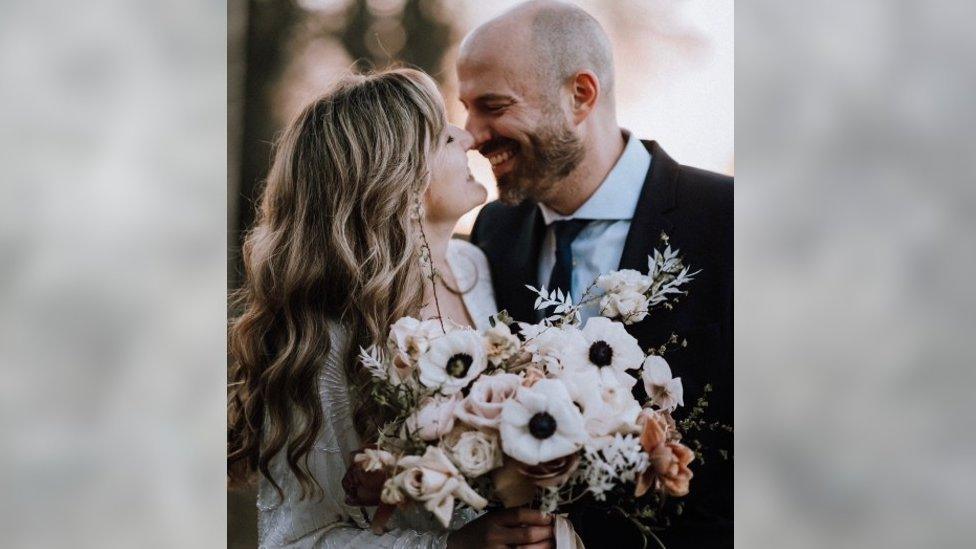 A woman smiling up at a man in a wedding outfit