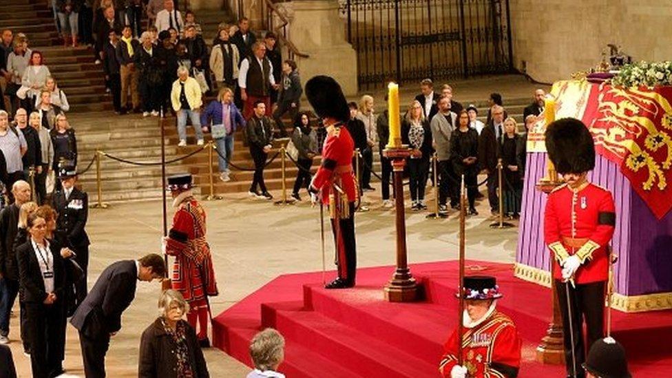 The Queen's coffin surrounded by members of the public, and watched over by royal staff