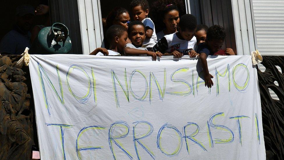 Refugees and asylum seekers protest against their eviction near gas cylinders and a banner reading 'We are not terrorists' on 23 August 2017