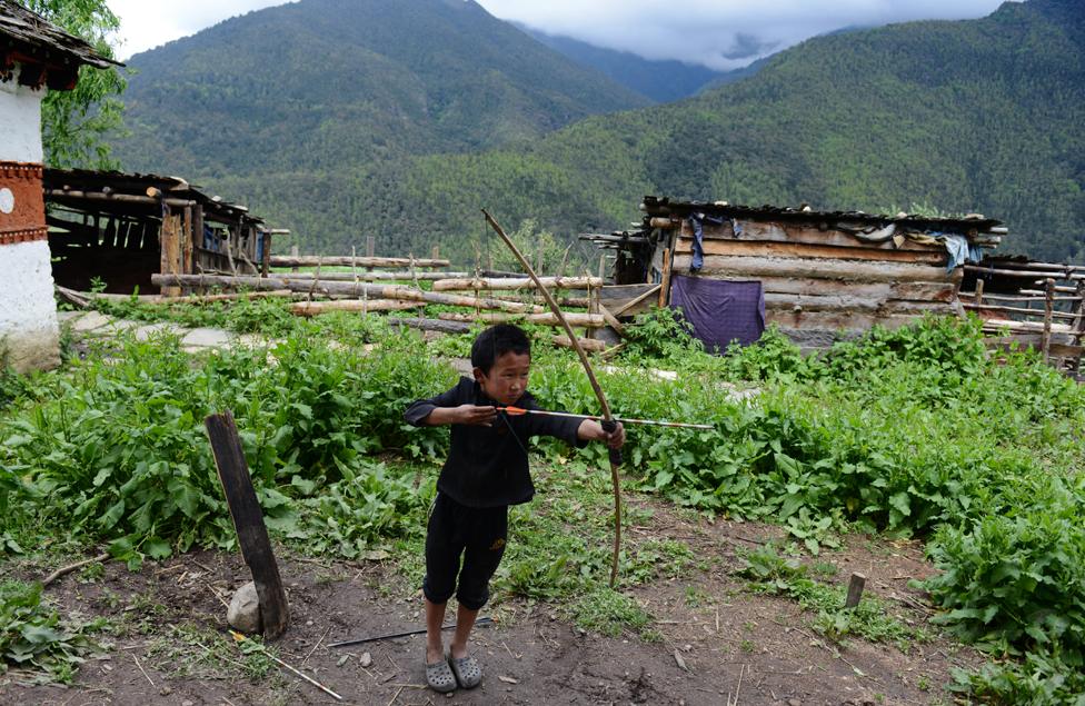 A boy practising archery in the mountains