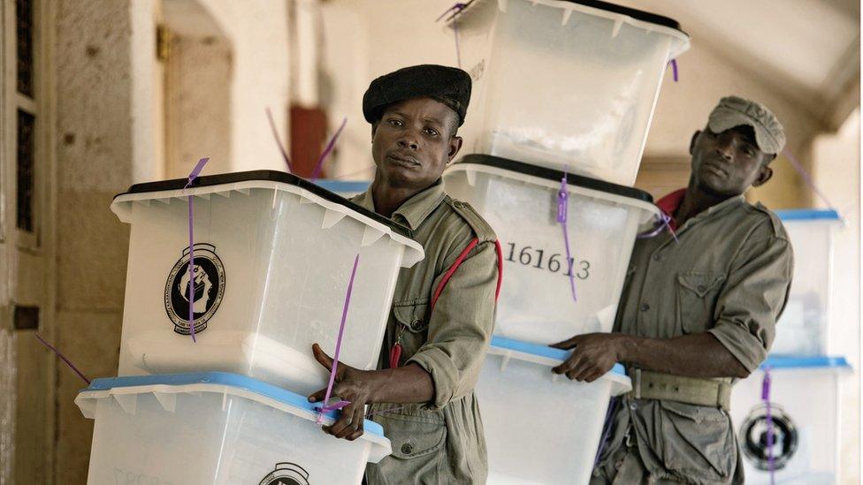 Security workers carry ballot boxes at a polling station in Dar es Salaam on October 26, 2015.