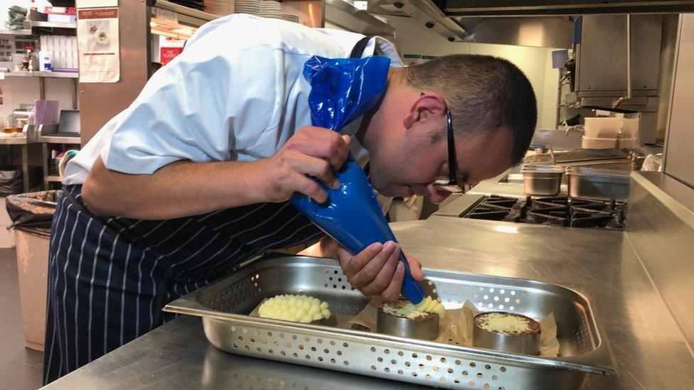 A man using a piping nozzle to bake