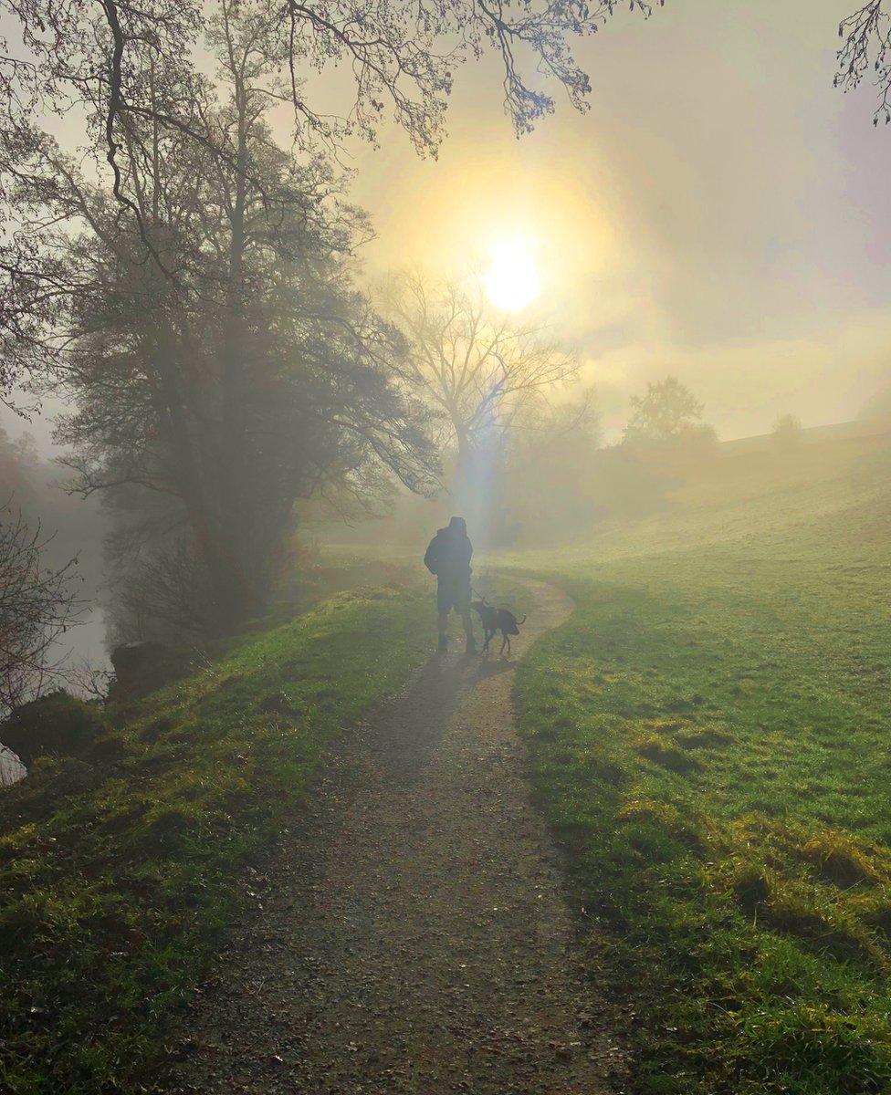 Mist around a dog walker in the village of Curbar in Derbyshire