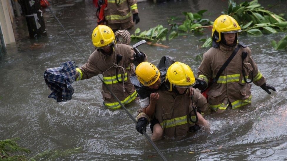 Rescuers carry a woman across a flooded street in Hong Kong