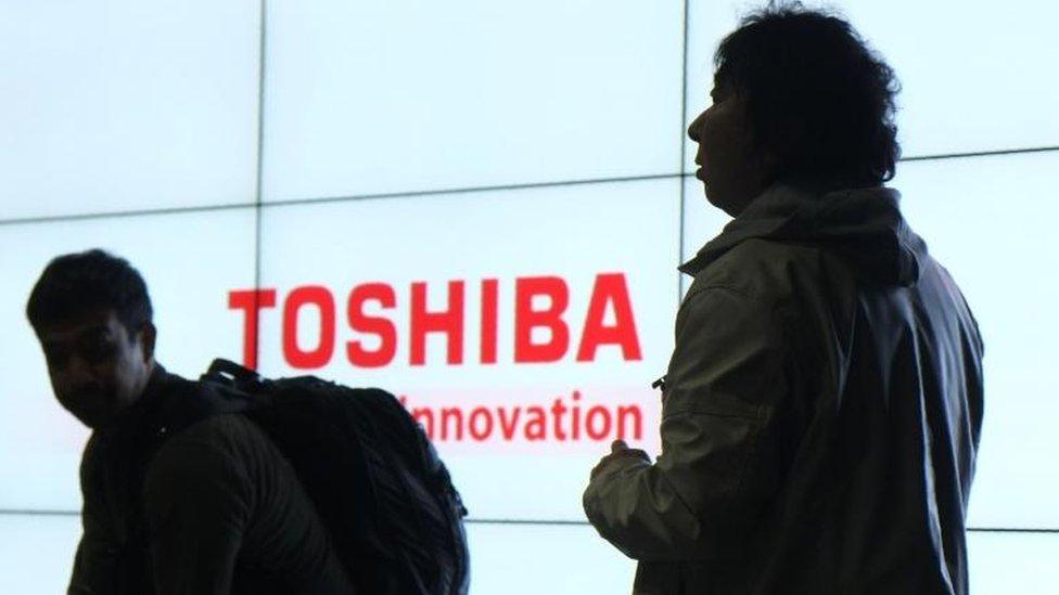 Journalists in front of a Toshiba sign