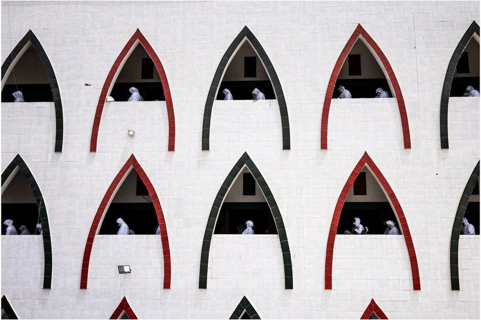 Muslim worshippers are seen through triangle-shaped recess windows.