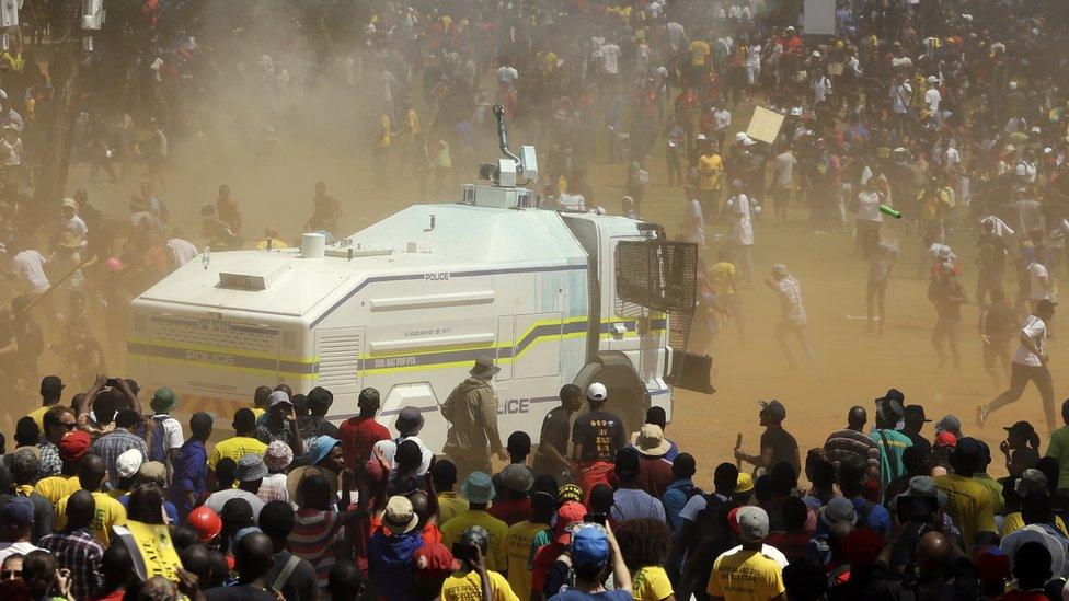 A police water cannon is swamped by protesting students during their protest against university tuition hikes outside the union building in Pretoria, South Africa