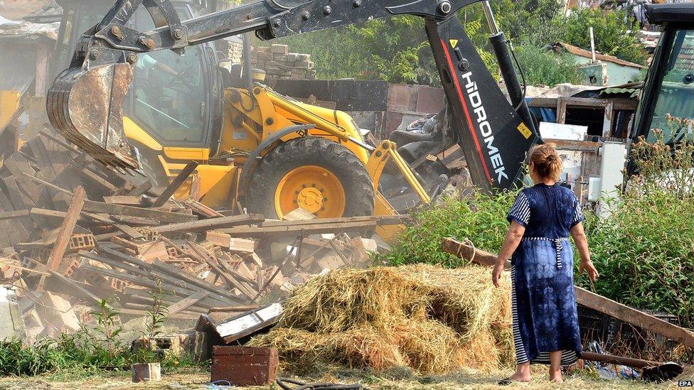 A woman looking on as heavy machines are used by Bulgarian authorities to demolish 50 illegally built homes in the Roma neighbourhood of Varna, 21 August 2015