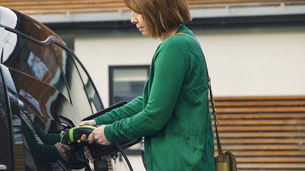 Stock image of a woman charging her electric car