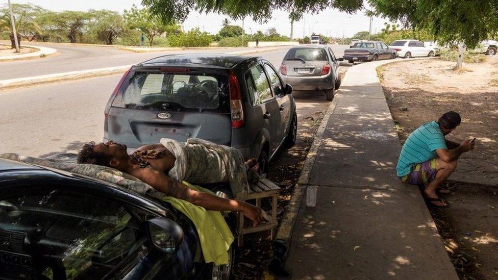 People wait next to their vehicles to load gasoline at a closed station, in Maracaibo, Venezuela, 19 September 2020