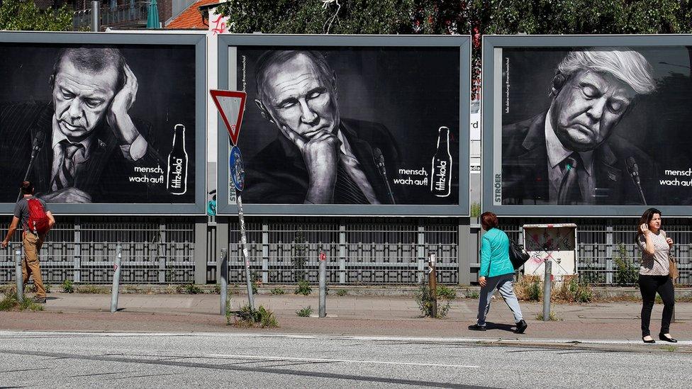 People walk past advertising posters of a German soft drink producer depicting Turkey"s President Tayyip Erdogan, Russian President Vladimir Putin and U.S. President Donald Trump during the G20 summit in Hamburg, Germany, July 6, 2017.