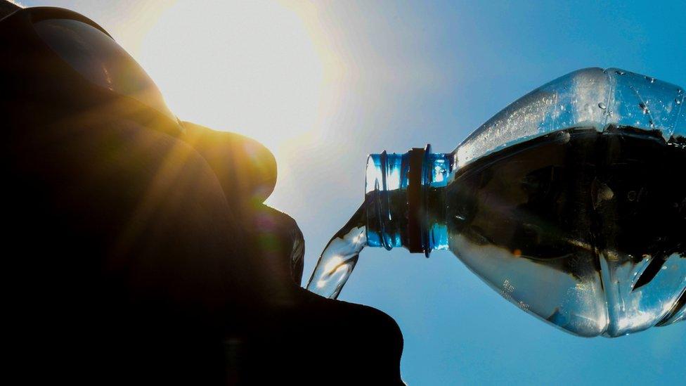 A man poses while drinking from a water bottle in the French city of Lille on 25 July, 2018