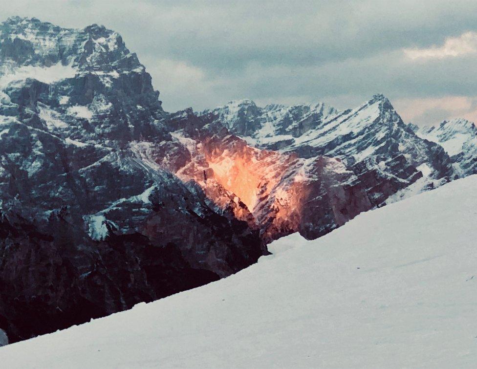 A golden sunset falls over the snowy mountains in the Dolomites